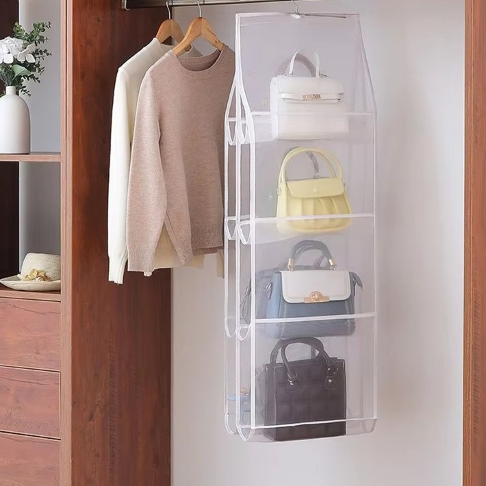 Hängeorganizer mit Handtaschen an einer Stange im Kleiderschrank neben zwei aufgehängten Pullovern