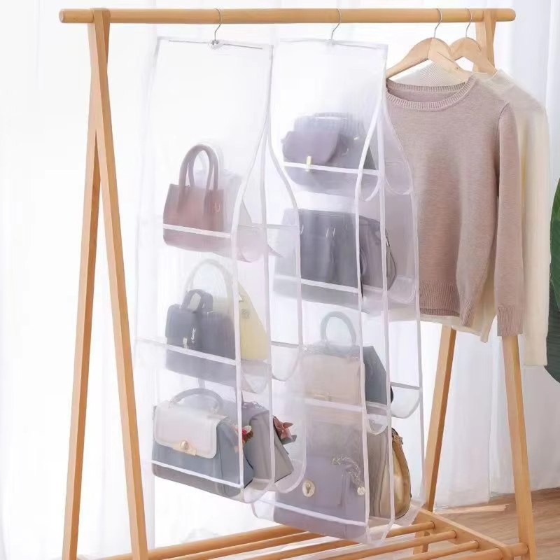 Zwei durchsichtige Hängeorganizer mit Handtaschen nebeneinander an einer Kleiderstange aus Holz, daneben hängen Pullover